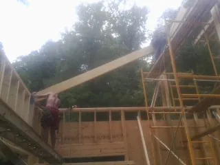 Carpenter raising a rafter beam on a new second story frame in Delmont