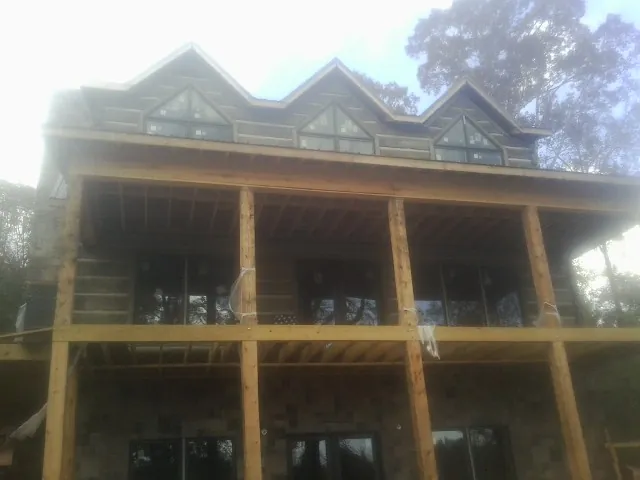 Dormers and porch framing on a large log home under construction — Roof Coating work by our crew in Delmont