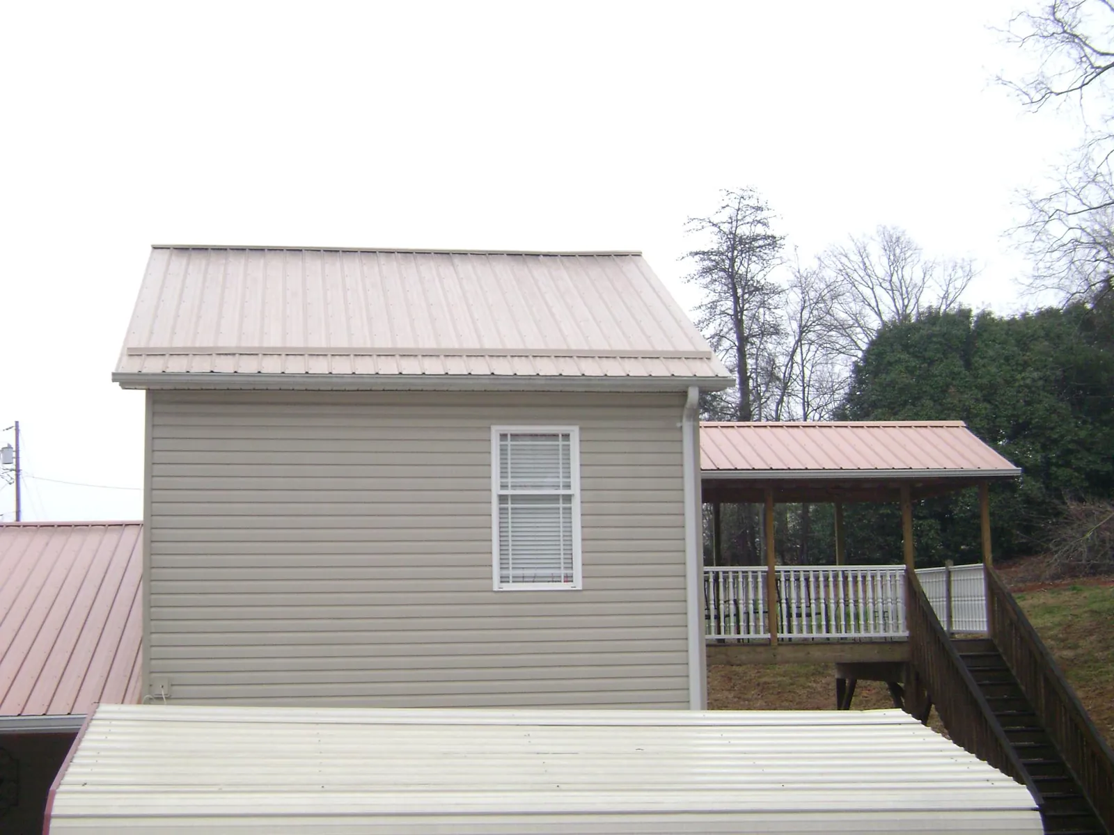 Tan metal roofs on a two story addition and attached porch, from a Roof Replacement job in Delmont